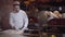 Young man in chef uniform cutting raw fish on cutting board. Cook separating fish fillet from bones. Food preparation in