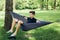 Young man chilling in hammock among trees. Social distancing. Small group of people enjoying conversation at picnic with social