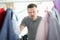 Young man choosing shirt in wardrobe closeup