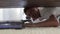 Young man cleaning a floor under a bed lying on the floor using vacuum cleaner