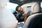 Young man cleans front seat of car with steam generator