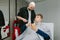 Young man client sits in a barber shop chair and shows a smartphone screen to his barber.Guy cuts his hair at a men`s hairdresser