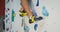 A young man climbs up the artificial surface of the climbing wall