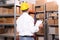 Young man with clipboard near rack of boxes at warehouse, back view