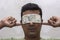 A young man closes his eyes with Indian currency notes and put his fingers in ears. Concept of corruption and power of money