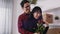 Young man closing eyes of his girlfriend with hand and gifting her with bouquet of red roses on wedding anniversary