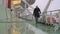 A young man in a coat walks along the empty deck of the ship.