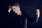 Young man comb his hair on black background. Portrait of handsome stylish caucasian boy is doing his hair style using a hair spray