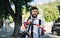 Young man commuter with headphones and bicycle walking outdoors in city.