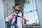 Young man commuter with headphones and bicycle walking outdoors in city.