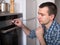 Young man controls the oven in the kitchen