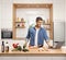 Young man cooking in a kitchen with a laptop