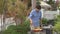 A young man cooks vegetables and shrimps on a barbeque in his backyard