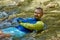 A young man cools off in the cold water of a mountain river on a hot summer day