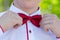 A young man corrects a red bow tie_