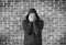 Young man covers his face with hands with bricks wall as background,black and white