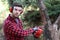 Young man cutting trees with electric chainsaw
