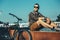 Young Man Cyclist Sitting On Fountain Next To Bicycle In Summer Park Daily Lifestyle Urban Resting Concept