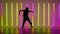 Young man dancing hip-hop against the background of bright neon lights. A silhouette of a dancer in everyday youth