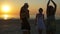 Young man dancing with three female friends on the shore of the ocean