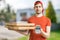 Young man is delivering pizza in boxes and holds payment terminal.