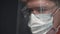 Young man doctor or nurse working. Male in medical mask, glasses and shield.