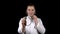 A young man doctor stands with with a stethoscope and listens on a black background. The man directed the hearing aid