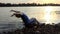 Young Man Does a Relaxing Exercise in a Folding Chair at Sunset