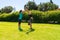 Young man doing handstands in the park with trainer assistance.