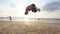 Young man doing parkour tricks on sea beach at sunset. Freerunner guy showing various jumps while running on ocean shore