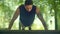 Young man doing push ups. Athletic man making pushups in park