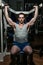 Young man doing shoulder press on machine in gym