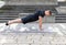 Young man doing a triangle push-up or diamond push-up outdoors on an exercise mat on concrete background