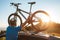 Young Man dresses modern cycling clothes and protective helmet installing his mountain bike on the car roof with sunset backlight