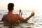 Young man with drink on inflatable ring in sea