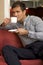 Young man drinking tea, sitting in sofa