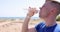 Young man drinking water by sea from plastic bottle in summer 4k movie