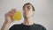 Young man drinks refreshing orange soda through a tube at white background