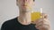 Young man drinks refreshing orange soda through a tube at white background