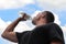 Young man drinks water against the background of clouds. quenches thirst. healthy lifestyle and health care