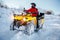 Young man driver in red warm winter clothes and black helmet on the ATV 4wd quad bike stand in heavy snow with deep