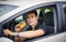 Young man driving his car while eating food