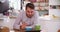 Young Man Eating Breakfast Whilst Using Digital Tablet