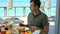 Young man eating brunch at restaurant in tropical hotel with turquoise sea background. Serious male tourist have