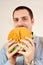 Young man eating a giant fake hamburger