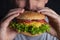 Young man eating tasty burger. Extreme close up. Male bite a cheeseburger