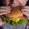 Young man eating tasty burger. Extreme close up. Male bite a cheeseburger