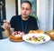 Young man eating vegetable salad and pulpo a la Gallega with potatoes. Galician octopus dishes. Famous dishes from Galicia, Spain