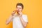 Young man eats a piece of appetizing pizza on a yellow background. Hungry guy holds a piece of pizza in his hands, looks at him