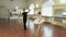 Young man and elderly woman dancing ballet synchronously in gym